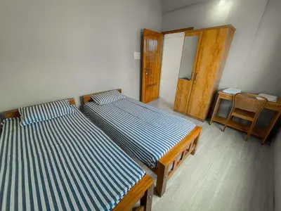 two beds in a room with a door and a chair at MB Arcade in Tellicherry