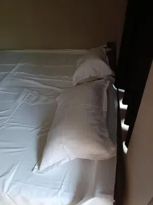 an unmade bed with white sheets and pillows at MB Arcade in Tellicherry