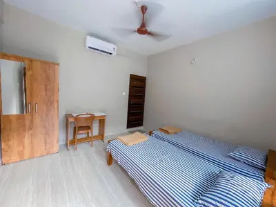 a bedroom with a bed and a table with a fan at MB Arcade in Tellicherry