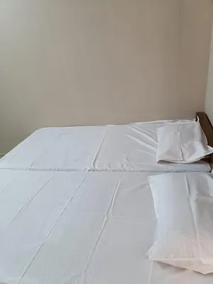 a white bed with white sheets and pillows on it at MB Arcade in Tellicherry