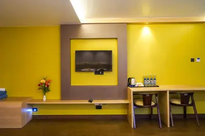 a room with a table and a tv on a wall at Trident in Ooty