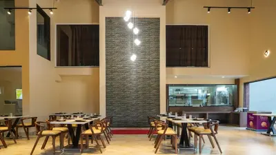 a restaurant with tables and chairs and a brick wall at Trident in Ooty