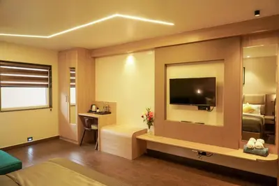 a hotel room with a television and a bedroom at Trident in Ooty