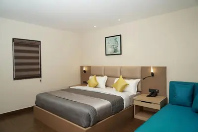 a bedroom with a bed and a blue chair at Trident in Ooty