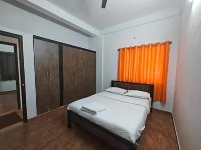 a bedroom with a bed with an orange curtain at Urban Nest Residence in Mysore