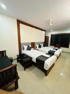 a room with two beds and a table at Royal Plaza City in Kozhikode