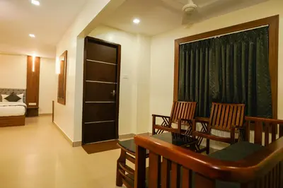 a room with a balcony with chairs and a bedroom at Royal Plaza City in Kozhikode