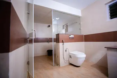 a bathroom with a toilet and a glass shower at Vista Sunrise Resort Ooty Dodabetta in Ooty