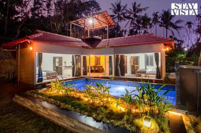 a villa with a swimming pool at night at StayVista at Palm Tree Homes with Complimentary Breakfast, BBQ Grill and Pet-Friendly Home in Wayanad