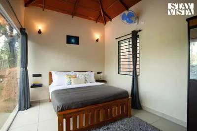 a bedroom with a bed and a window at StayVista at Palm Tree Homes with Complimentary Breakfast, BBQ Grill and Pet-Friendly Home in Wayanad