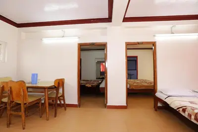 a room with a table and chairs and a bedroom at Hotel Sri Balaji in Ooty