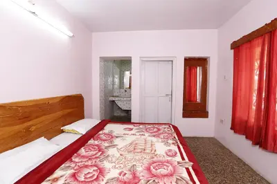 a bedroom with a bed with a floral blanket on it at Hotel Sri Balaji in Ooty