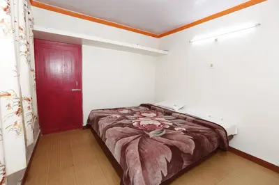a bed in a room with a red door at Hotel Sri Balaji in Ooty