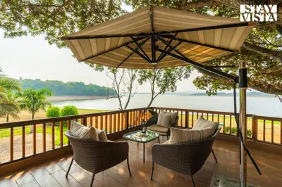 a patio with chairs and a table and an umbrella at StayVista at Exotica Kabini - All Meals Included - Riverfront Villa in Antarasante
