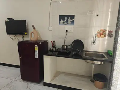 a kitchen with a counter and a sink and a refrigerator at The Whispering Willows in Mysore