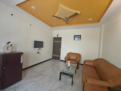 a living room with a couch and a ceiling fan at The Whispering Willows in Mysore
