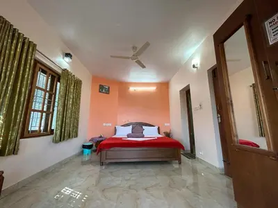 a bedroom with a bed with orange walls and a ceiling at Madhu Manish Homestay and Rooms in Coonoor
