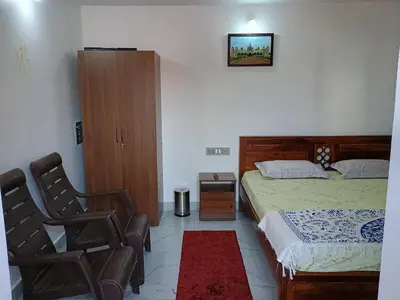 a bedroom with a bed and two chairs in it at Vigneshwara Nilaya in Mysore