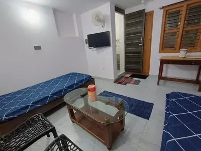 a room with a bed and a table and a tv at Vigneshwara Nilaya in Mysore