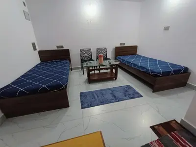 two beds and a table in a room with rugs at Vigneshwara Nilaya in Mysore