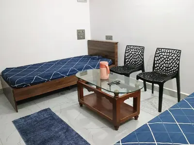 a bedroom with a bed and two chairs and a table at Vigneshwara Nilaya in Mysore