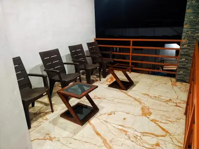 a room with chairs and a table on a marble floor at Centre Home Homestay Wayanad in Kalpetta