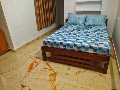 a bedroom with a bed with a blue comforter at Centre Home Homestay Wayanad in Kalpetta