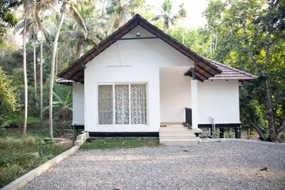 a small white house in the middle of a road at Peechi Green Valley in Pattikad