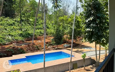 a swimming pool in the middle of a yard with trees at Peechi Green Valley in Pattikad