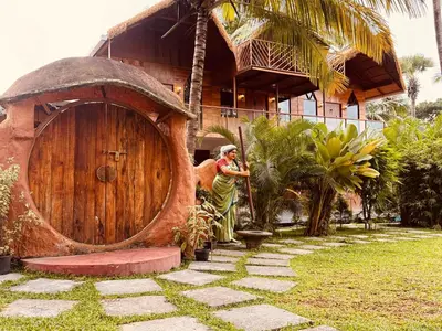 a woman standing in front of a large wooden door at Udaya Resort in Palakkad