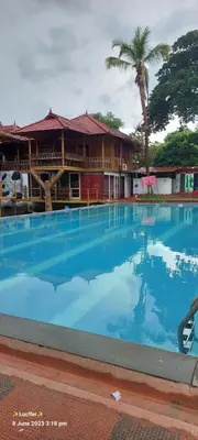 a large blue swimming pool in front of a building at Udaya Resort in Palakkad