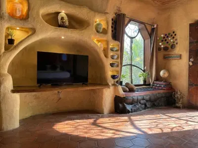 a living room with a flat screen tv in a stone wall at Udaya Resort in Palakkad