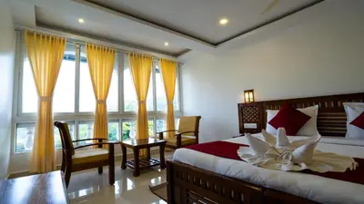 a bedroom with a bed and a table and some windows at Carmel Top Munnar in Munnar