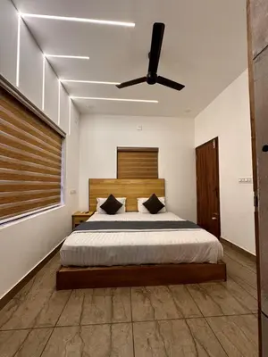 a bedroom with a bed with a ceiling fan at Grandstaykannur in Kannur