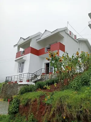 a house on a hill with flowers in front of it at Phoenix View Stay Ooty in Ooty