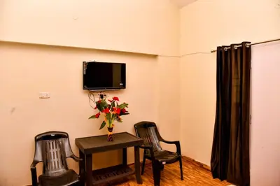 a room with a table and two chairs and a tv at Phoenix View Stay Ooty in Ooty