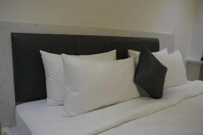 a bed with white pillows and a black headboard at Goldeye's Inn in Erode