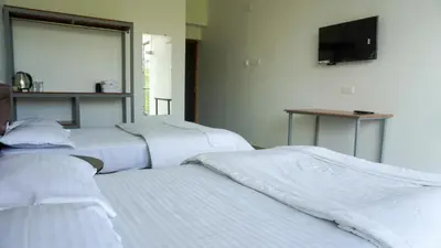 three white beds in a room with a television at Zen Vista in Vālpārai