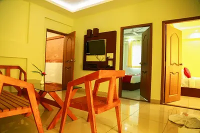 a living room with a television and a table and chairs at AKAN HOTEL AND RESIDENCE in Wayanad