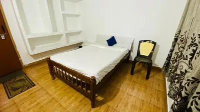 a small bed and a chair in a room at Misty Green Coorg in Madikeri