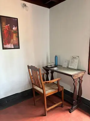 a wooden table and a chair next to a table at Vilayara Heritage Retreat in Kunnamangalam