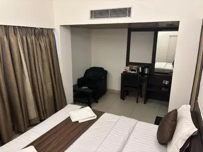 a bedroom with a bed and a chair and a desk at WESTLAND HOTEL- ERODE in Erode
