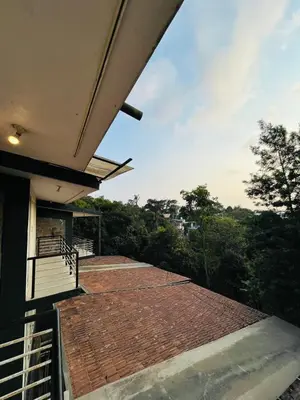 a balcony of a house with a roof at Red Stone Villas in Madikeri