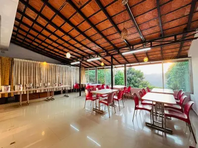 a dining room with tables and chairs and windows at Red Stone Villas in Madikeri