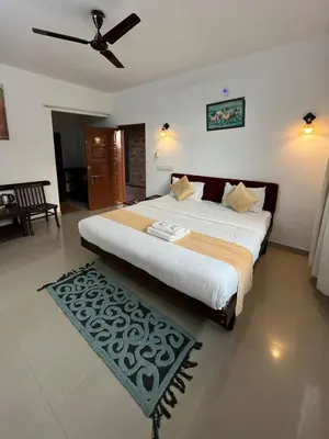 a bedroom with a large bed with a ceiling fan at Red Stone Villas in Madikeri