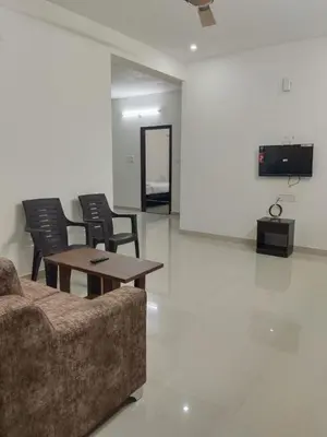 a living room with a couch and a table and chairs at ORCHID ELITE BRINDAVAN in Mysore