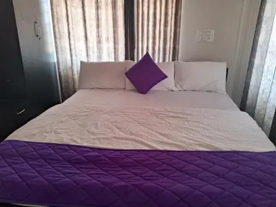 a purple and white bed with a purple pillow on it at Royal homes a2 in Kushālnagar