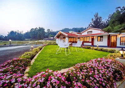 two chairs sitting on a lawn in front of a house at Lauriston Ooty Town Heritage Bungalow by VOYE HOMES in Ooty
