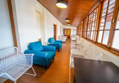 a waiting room with blue chairs and tables and windows at Lauriston Ooty Town Heritage Bungalow by VOYE HOMES in Ooty