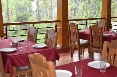 a restaurant with tables and chairs with red tablecloths at Ibbanicadu Estate Homestay in Madikeri